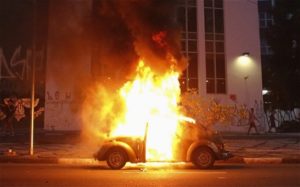 A car burns after the family riding it drove through a flaming barrier during a protest against the 2014 World Cup in Sao Paulo