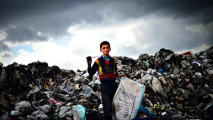 A young Syrian boy holds a bag as he col...A young Syrian boy ho