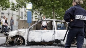 French police stand guard near a car destroyed in overnight clashes where gangs of youths set cars, bins and a school ablaze in Amiens August 14, 2012. About 100 youths burned cars, a leisure centre and a nursery school according to an official from the prefect's office. REUTERS/Pascal Rossignol (FRANCE - Tags: CRIME LAW) - RTR36TYR
