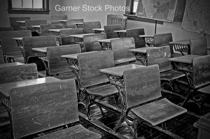 This photo is an vintage, turn of the century old school classroom with the wooden desks, wood floors, old radiator and vintage maps.  Full of rich tradition of an American school in the early 1900's.  Background intentionally soft for artistic effect.